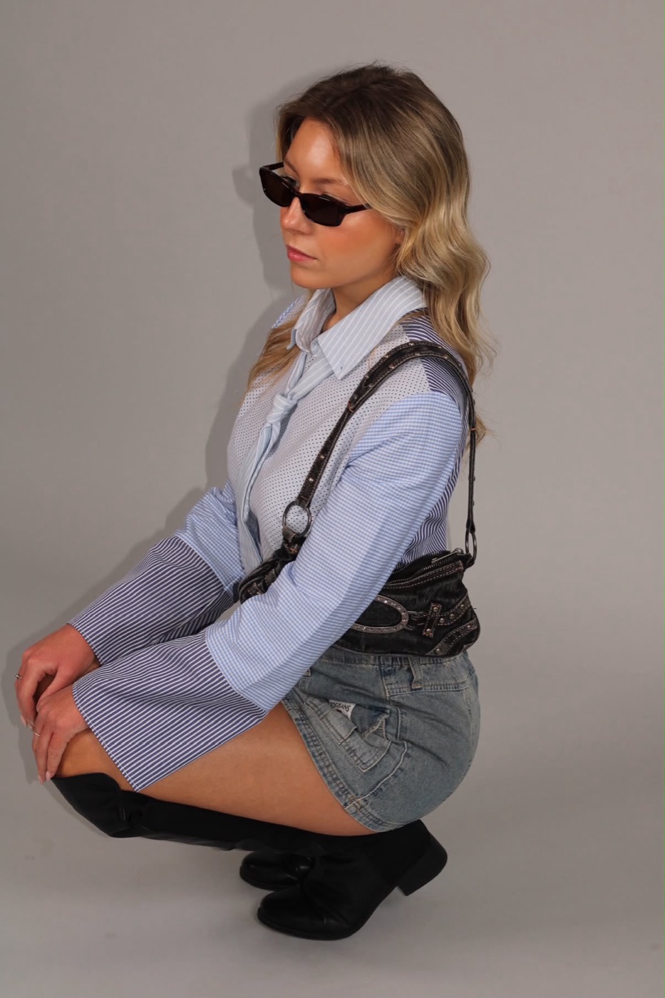 Liberty crouching in the reworked shirt, sunglasses and knee boots