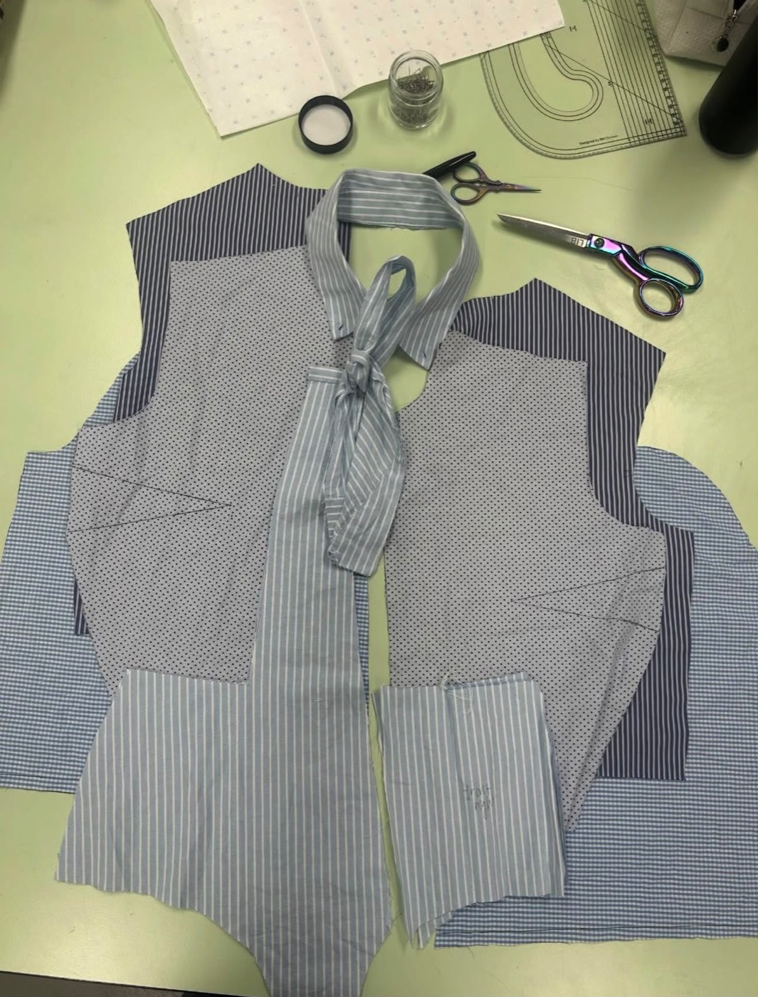 Shirts cut into new pattern pieces laid out with scissors and pattern curves